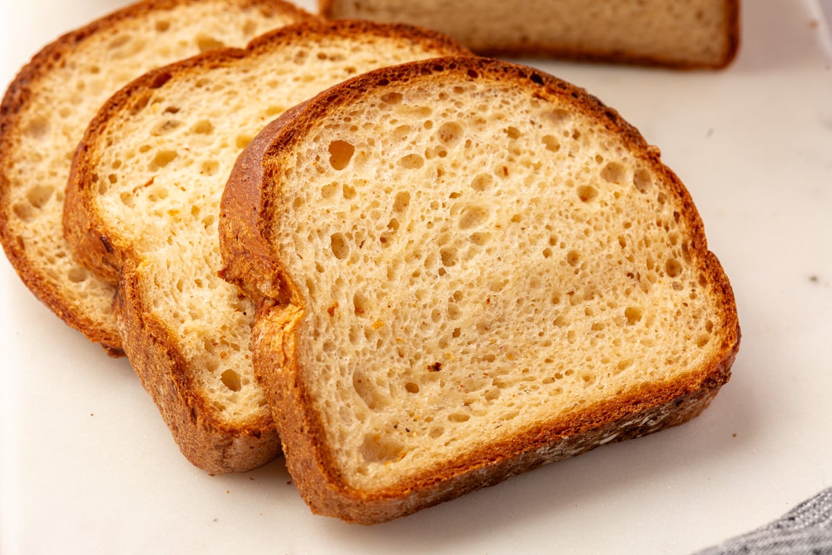 Three slices of toasted gluten-free bread overlapping on a white surface.