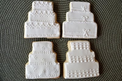 Four wedding cake sugar cookies on a placemat.