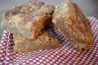Snickerdoodle blondies stacked on top of each other on a red and white checked napkin.