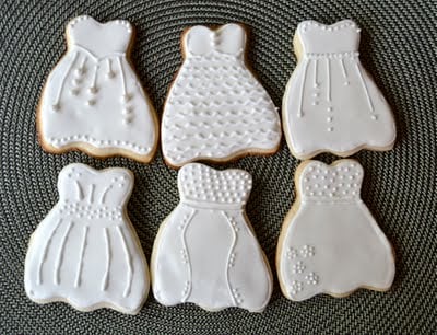 Six wedding dress sugar cookies on a placemat. 