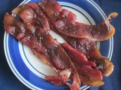 A few pieces of candied bacon on a blue and white plate.