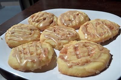 A plate of cinnamon roll cookies with a drizzle of cinnamon glaze.