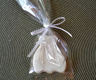 A wedding dress sugar cookie in a plastic bag tied with a bow.