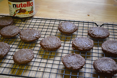 Nutella cookies on a cooling rack with a jar of nutella behind it.