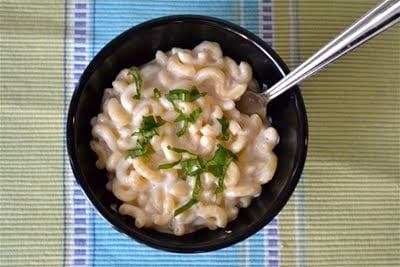 A bowl of mozzarella mac and cheese topped with basil.