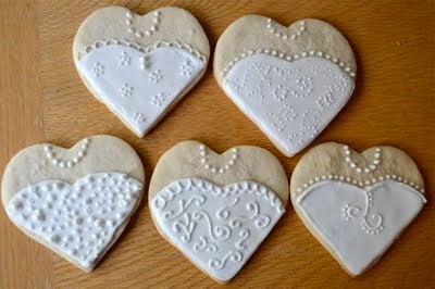 Five heart shaped wedding dress sugar cookies on a wooden table.