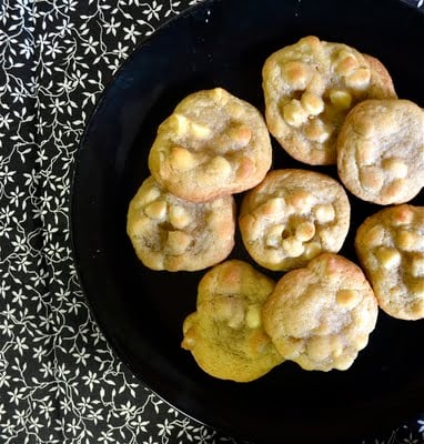 White chocolate macadamia nut cookies on a black plate with black and white floral napkin.