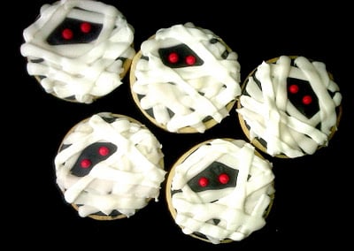 Five sugar cookies decorated like mummies.