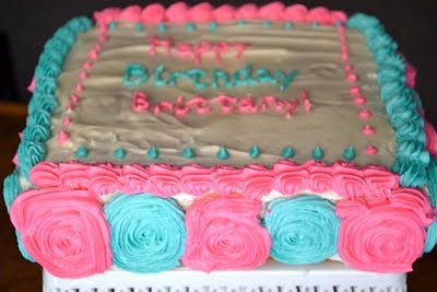 A vanilla cake with pink and blue buttercream decorations.