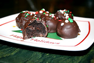 Chocolate cake balls topped with red, green and white sprinkles on a Christmas plate.